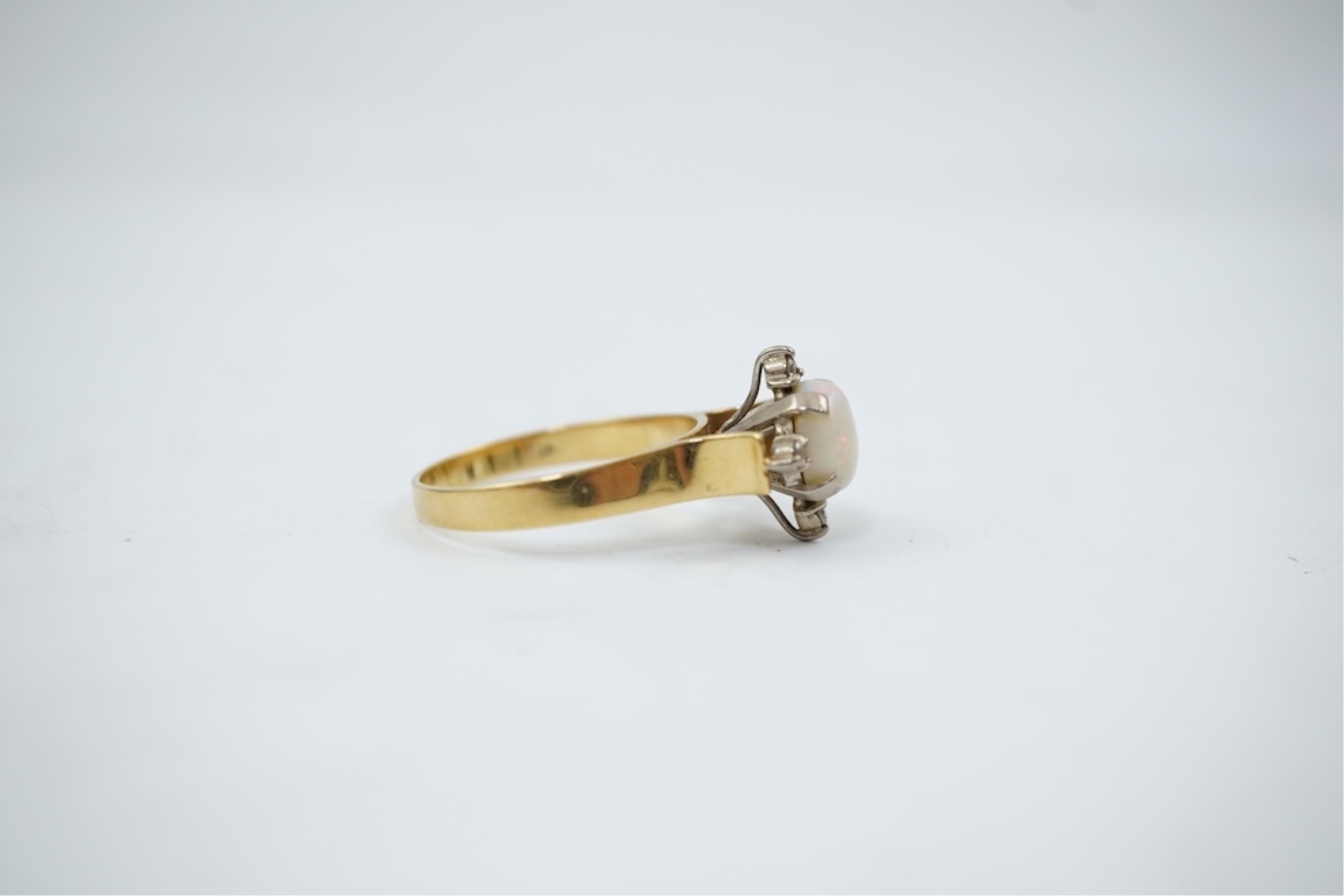 A yellow metal (stamped 18), single stone white opal and four stone diamond chip set ring, size P/Q, gross weight 3.8 grams.